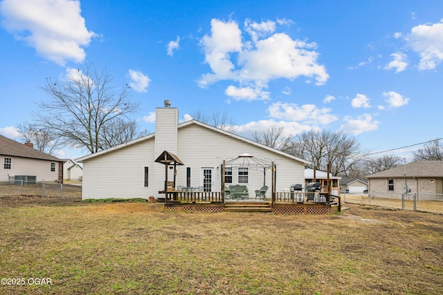 rear view of house with a gazebo, a deck, and a lawn