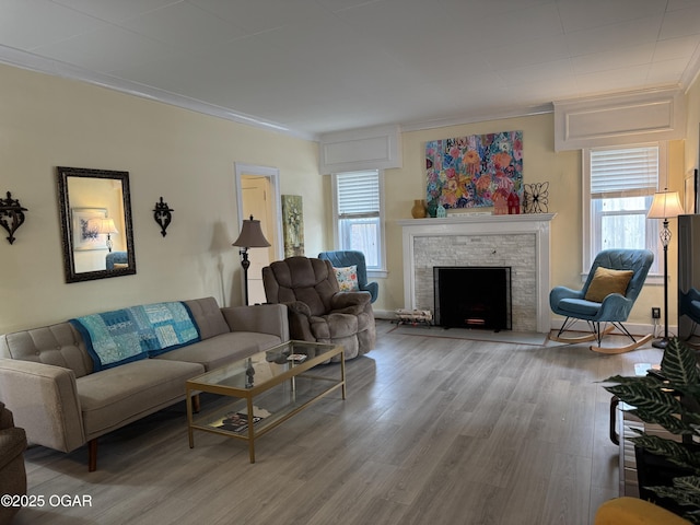 living room with crown molding, a fireplace, and light hardwood / wood-style floors