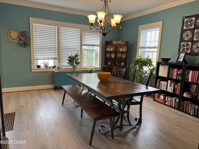 dining area with ornamental molding, a healthy amount of sunlight, a chandelier, and light wood-type flooring