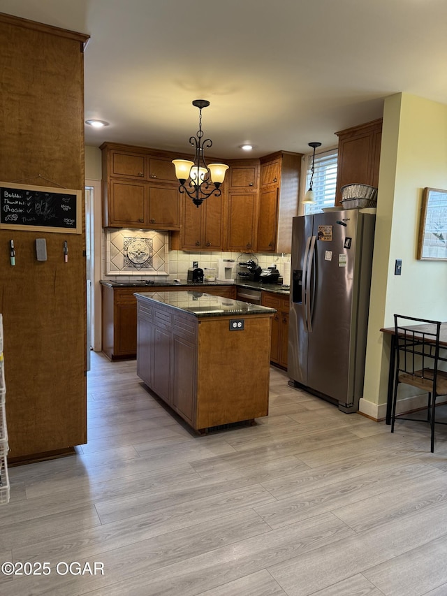 kitchen featuring a kitchen island, decorative light fixtures, backsplash, a chandelier, and stainless steel fridge with ice dispenser