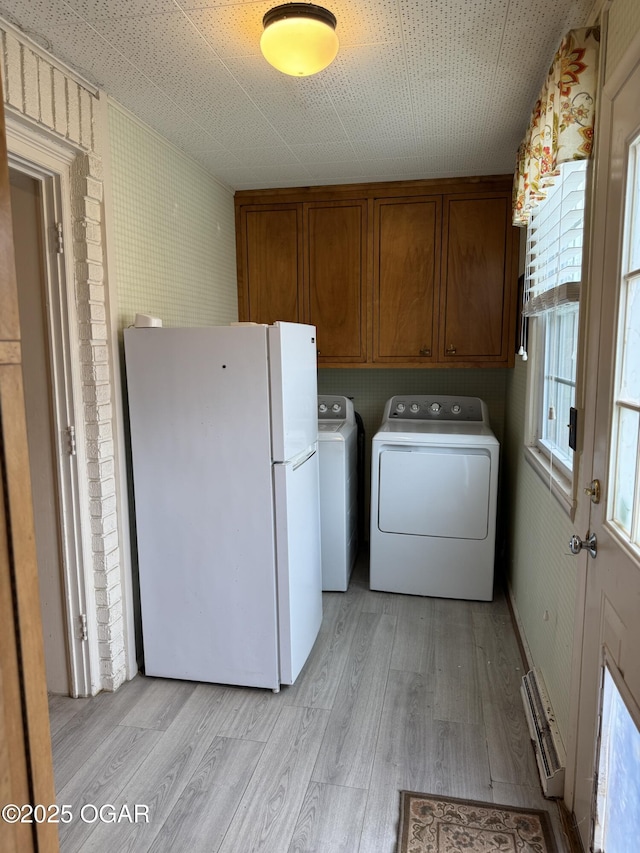 laundry room with cabinets, light hardwood / wood-style floors, and washer and dryer