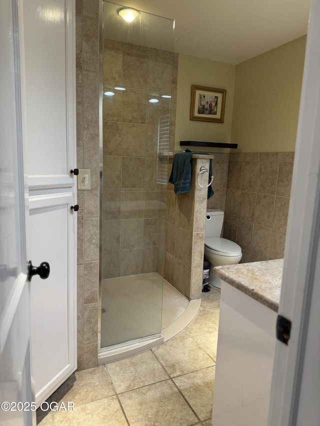 bathroom featuring tile patterned flooring, vanity, tile walls, and a tile shower