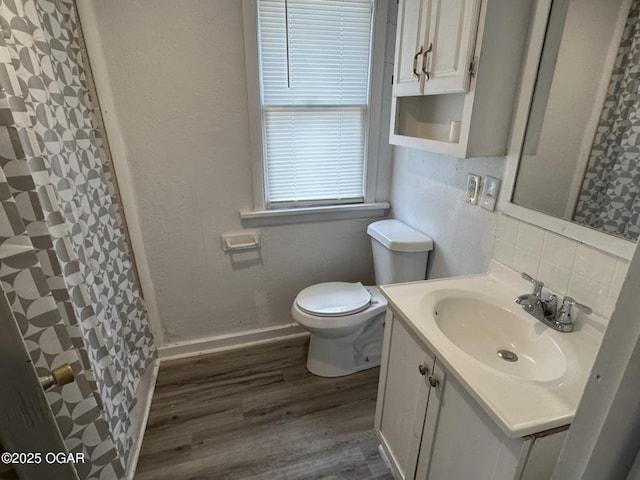 bathroom featuring tasteful backsplash, wood-type flooring, vanity, and toilet