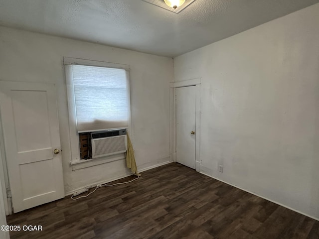 empty room with dark wood-type flooring, cooling unit, and a textured ceiling