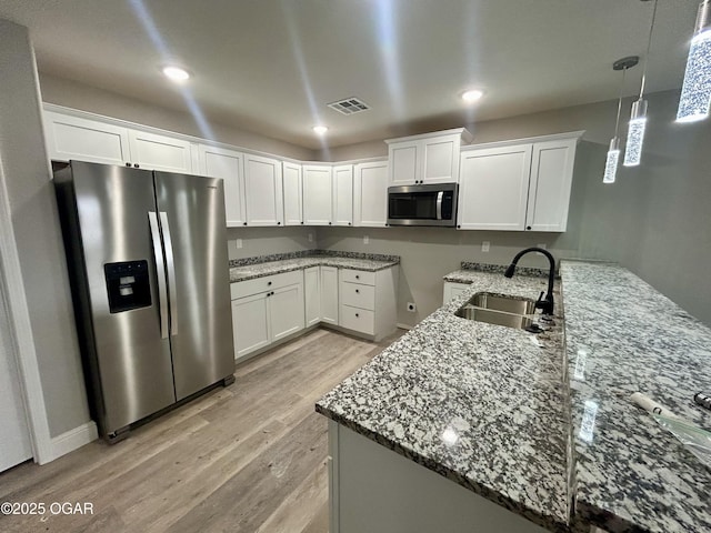 kitchen featuring white cabinetry, appliances with stainless steel finishes, light stone countertops, and sink