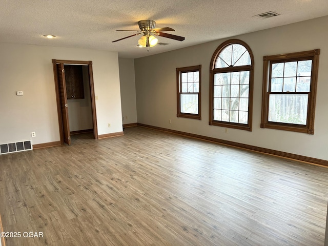 spare room with ceiling fan, light hardwood / wood-style flooring, and a textured ceiling