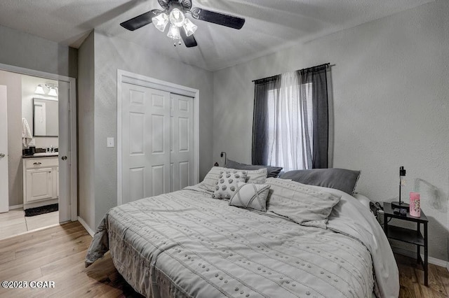 bedroom with connected bathroom, sink, ceiling fan, light wood-type flooring, and a closet