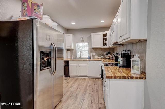 kitchen featuring stainless steel refrigerator with ice dispenser, sink, white cabinetry, wooden counters, and white dishwasher