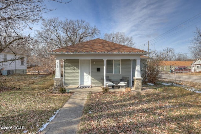 bungalow-style home featuring cooling unit, a front lawn, and covered porch