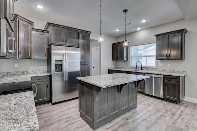 kitchen featuring sink, hanging light fixtures, a center island, stainless steel appliances, and light wood-type flooring