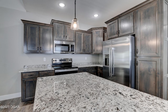 kitchen with decorative light fixtures, dark hardwood / wood-style flooring, light stone counters, stainless steel appliances, and dark brown cabinets