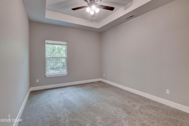 spare room featuring carpet flooring, ceiling fan, and a tray ceiling