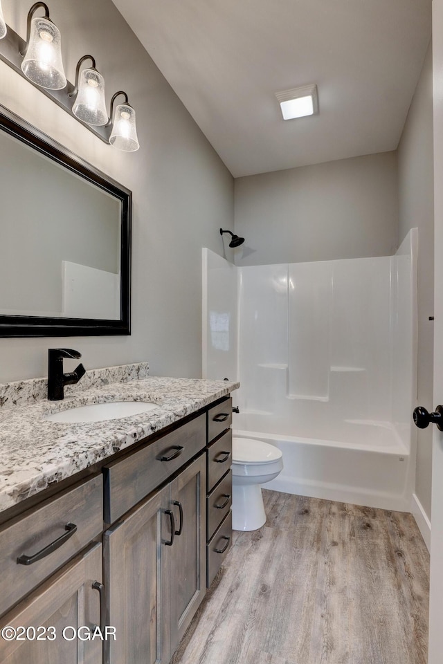 full bathroom featuring hardwood / wood-style flooring, shower / tub combination, vanity, and toilet