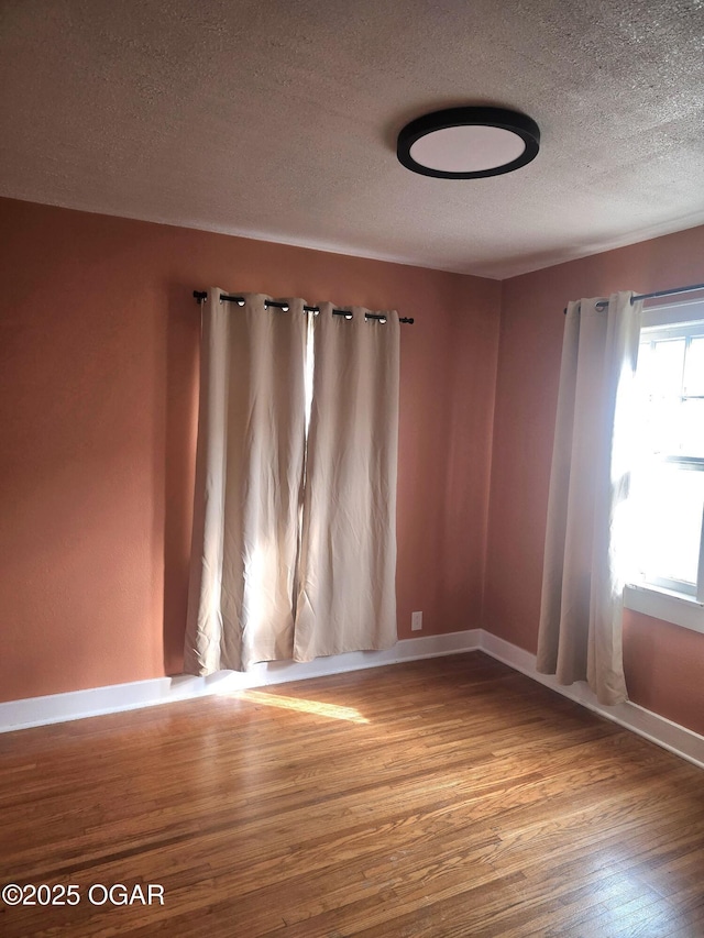 unfurnished room featuring hardwood / wood-style floors and a textured ceiling