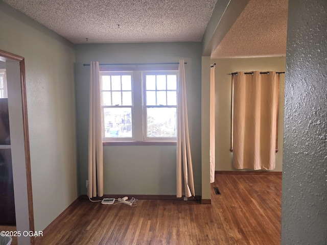 unfurnished room with wood-type flooring and a textured ceiling