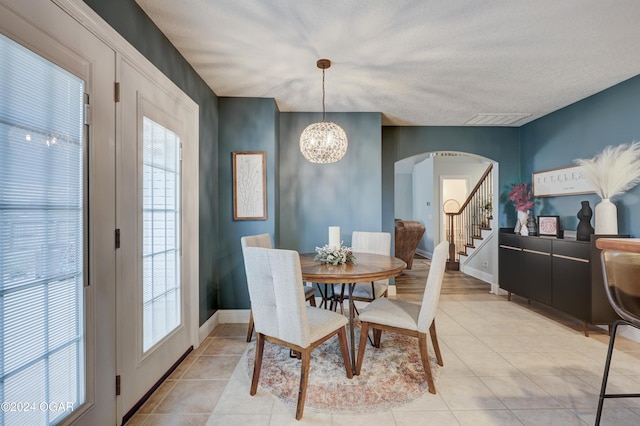 dining area featuring light tile patterned flooring, a notable chandelier, and a textured ceiling