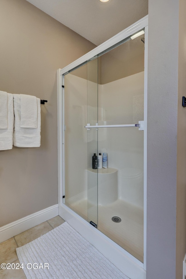 bathroom with an enclosed shower and tile patterned floors