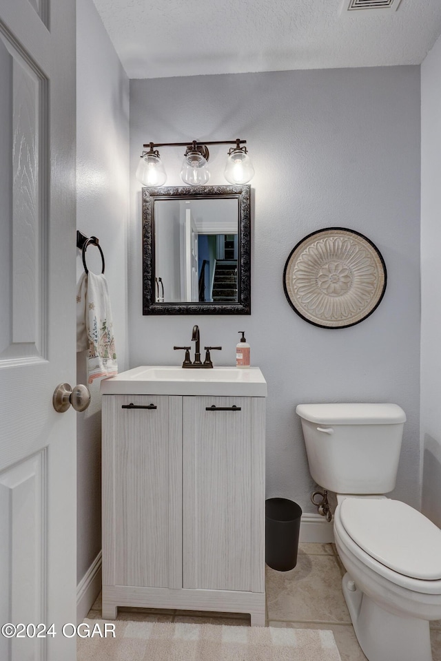 bathroom with vanity, tile patterned flooring, a textured ceiling, and toilet