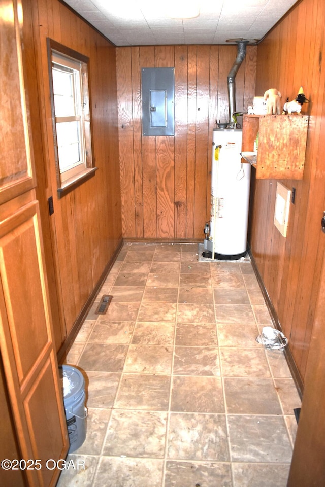 hall featuring electric panel, water heater, and wood walls