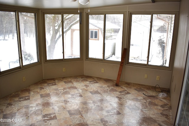 unfurnished sunroom featuring ceiling fan