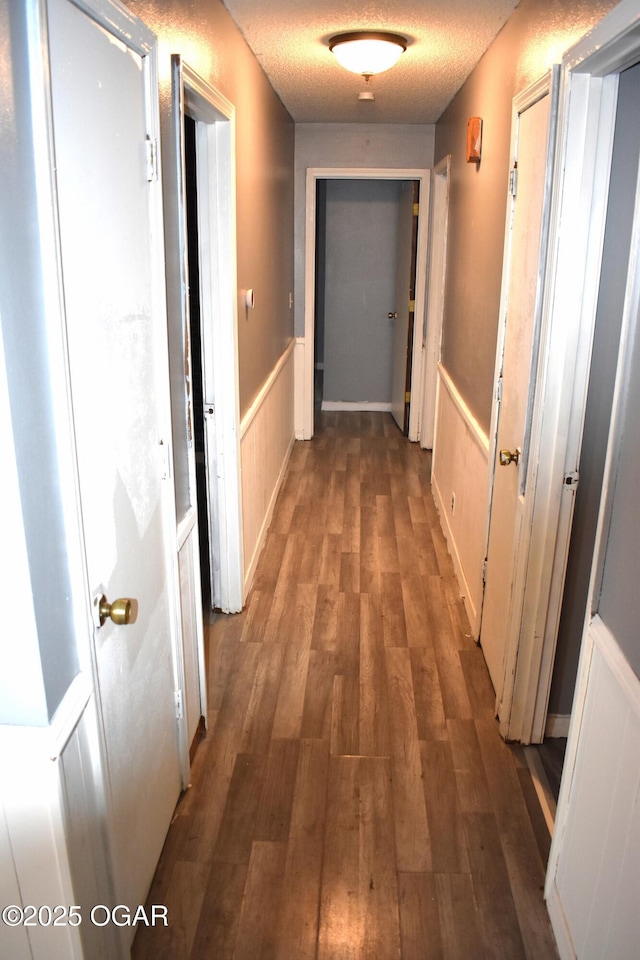 hall with dark hardwood / wood-style flooring and a textured ceiling