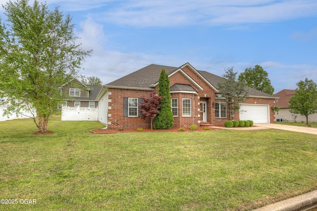 view of front of house featuring a front lawn, fence, brick siding, an attached garage, and driveway