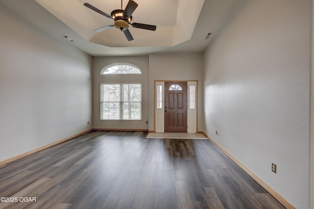 foyer featuring visible vents, a towering ceiling, wood finished floors, baseboards, and ceiling fan