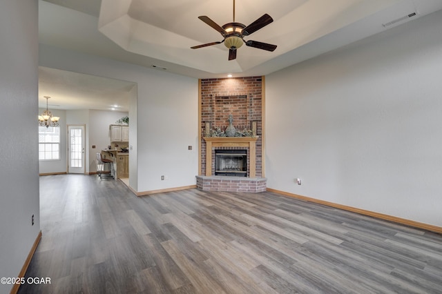 unfurnished living room with baseboards, visible vents, wood finished floors, and ceiling fan with notable chandelier
