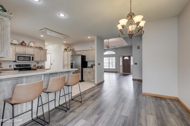 kitchen with appliances with stainless steel finishes, light wood-style flooring, recessed lighting, baseboards, and a kitchen bar
