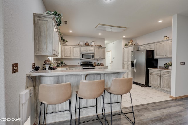 kitchen featuring recessed lighting, a peninsula, a kitchen breakfast bar, and stainless steel appliances