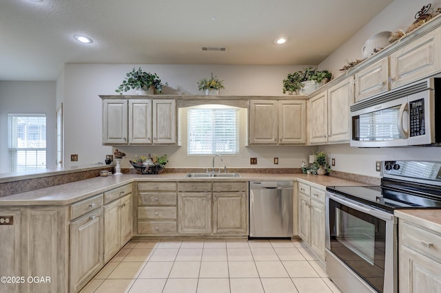 kitchen with light brown cabinetry, stainless steel appliances, visible vents, and a sink