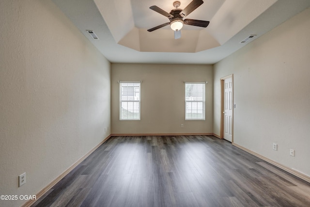 empty room featuring baseboards, ceiling fan, visible vents, and dark wood finished floors