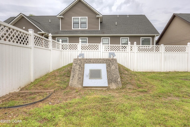 view of storm shelter featuring a fenced backyard and a yard