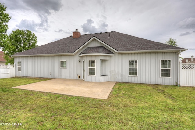 back of property featuring fence, roof with shingles, a chimney, a lawn, and a patio