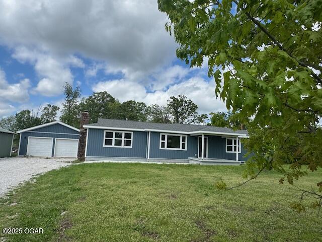 single story home featuring a front lawn, an outbuilding, and a detached garage
