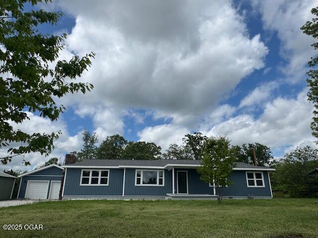 single story home with a chimney, an attached garage, and a front yard