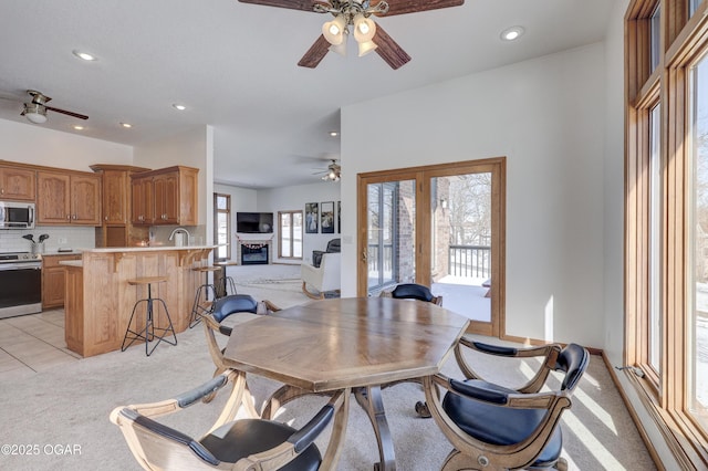 carpeted dining space featuring ceiling fan and sink