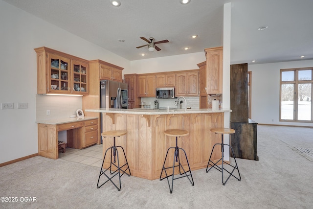 kitchen with light colored carpet, stainless steel appliances, kitchen peninsula, and a breakfast bar area