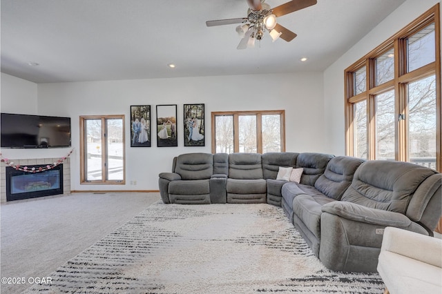 carpeted living room with ceiling fan, plenty of natural light, and a fireplace