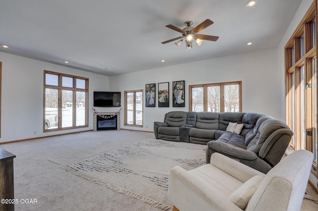 carpeted living room featuring a fireplace and ceiling fan