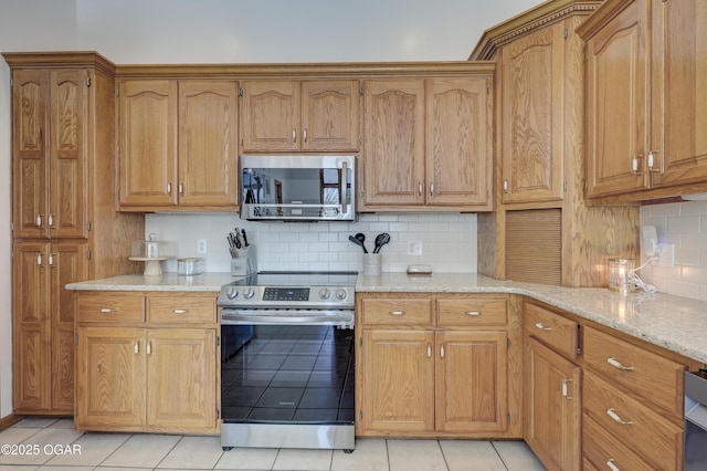 kitchen featuring tasteful backsplash, stainless steel appliances, light stone countertops, and light tile patterned floors