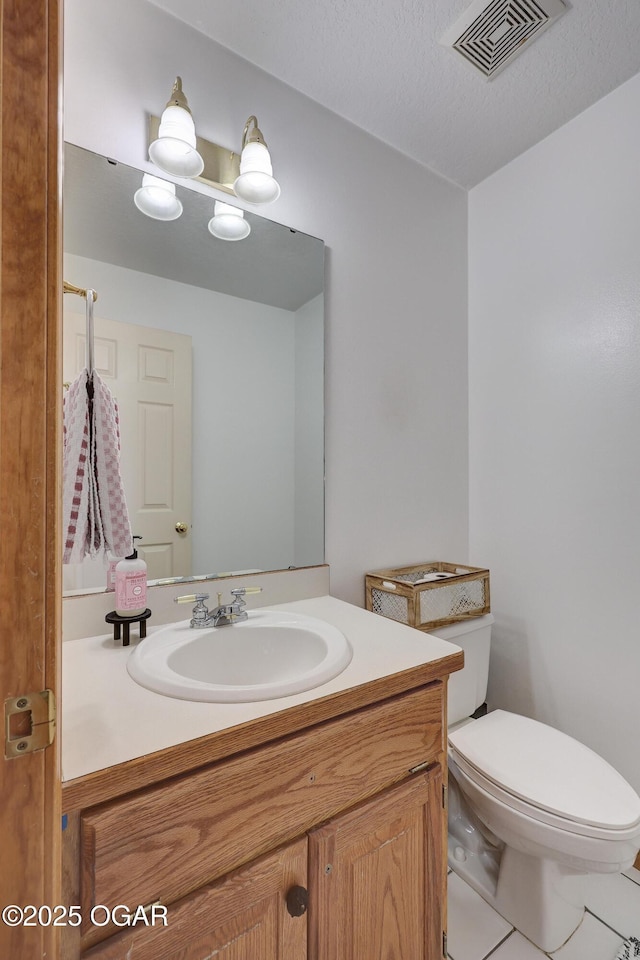 bathroom featuring vanity, toilet, and a textured ceiling