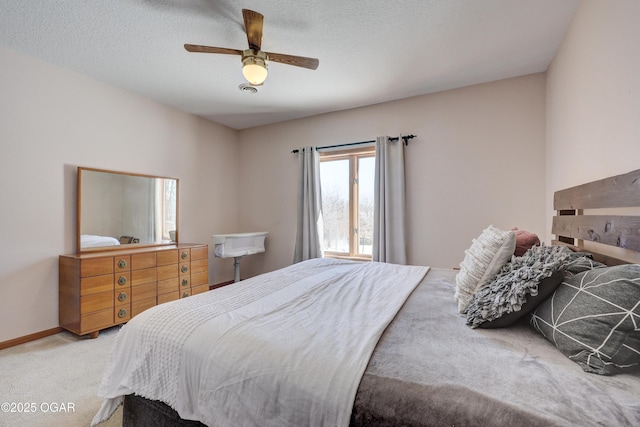 carpeted bedroom with ceiling fan and a textured ceiling