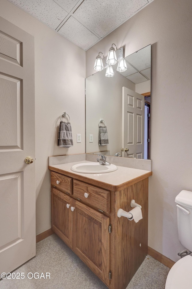 bathroom featuring vanity, a paneled ceiling, and toilet