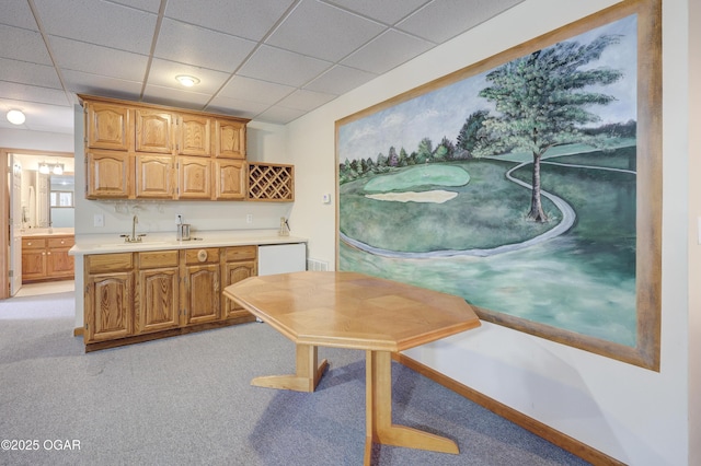 kitchen with dishwasher, sink, light colored carpet, and a drop ceiling