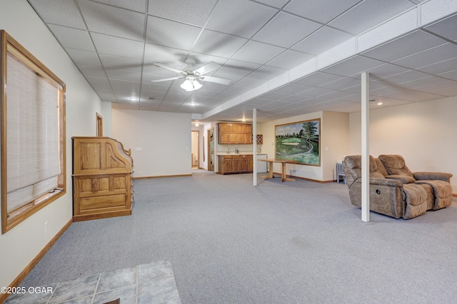 basement featuring ceiling fan, sink, light carpet, and a drop ceiling