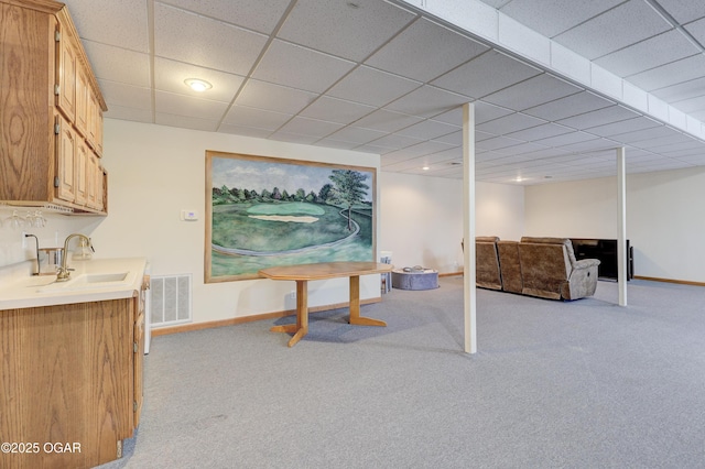 basement featuring sink, light carpet, and a drop ceiling