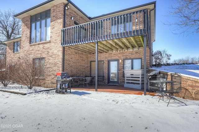 snow covered property featuring a balcony and a deck