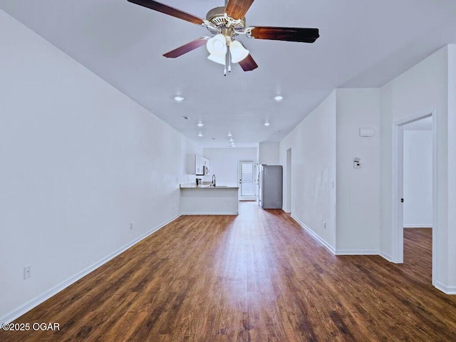 unfurnished living room featuring baseboards, a ceiling fan, dark wood-style floors, a sink, and recessed lighting