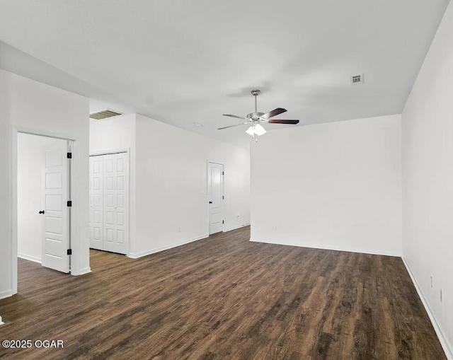 unfurnished room featuring ceiling fan, dark wood-type flooring, visible vents, and baseboards